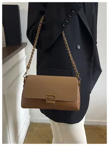 Detail of two-tone brown patchwork handbag with gold geometric lock and chain strap