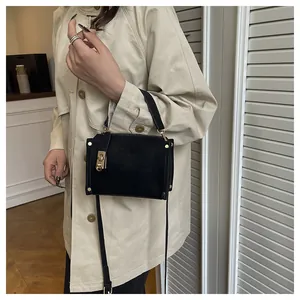 Close-up of black crossbody bag with gold buckle detail and stylish rivet accents