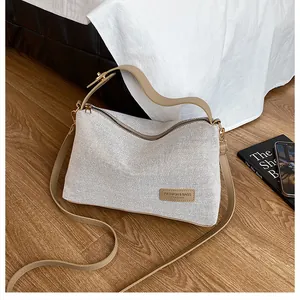 Macro shot of linen textured tote with leather strap and fashion label on wood floor