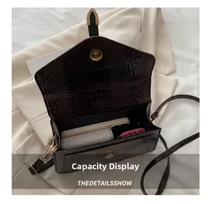 Detail showing internal capacity of dark brown crocodile pattern bag with phone and items