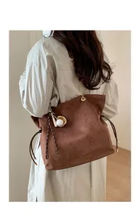 Detailansicht einer braunen Wildleder-Tote-Bag mit Kettenriemen und Baseball-Handschuh-Anhänger