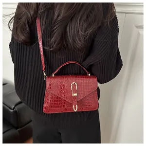 Detail view of red faux crocodile leather handbag with elegant gold hardware lock