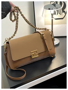 Detail of two-tone brown leather bag featuring a gold geometric buckle and chain strap