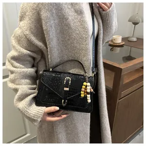 Detail of black crocodile texture handbag with colorful wood bead tassel on the side