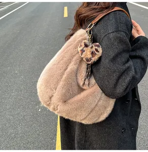 Detail of plush khaki hobo tote with heart leopard charm worn on shoulder outdoors