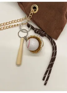 Dettaglio ciondolo a tema baseball con mazza in legno e guanto su borsa a secchiello marrone