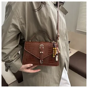 Detail of vintage brown crocodile texture handbag with beads pendant and metal buckle