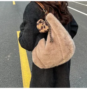 Back view of plush camel tote bag with leopard heart charm on a city street background