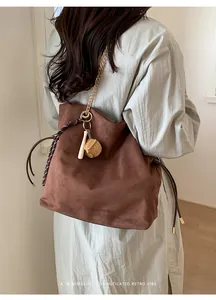 Dettaglio della borsa tote in pelle scamosciata marrone con catena dorata e ciondolo mini