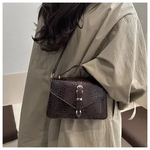 Detail of vintage brown crocodile embossed bag with metal buckle on khaki outfit