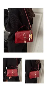 Detail of red crocodile texture handbag with golden hardware and colorful bead charm
