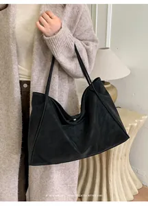 Detail of a large black suede tote bag with minimalist retro vibe and slim shoulder straps