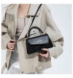 Détail d'un sac bandoulière noir vintage avec texte doré et motif logo texturé
