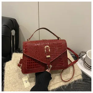 Detail of burgundy crocodile-embossed flap bag featuring elegant golden horseshoe clasp