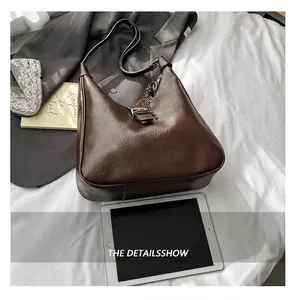 Detail view of deep brown vintage Hobo bag with metal buckle and silver chain accessory
