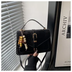 Detail of black crocodile texture handbag featuring golden horsebit buckle and colorful beads