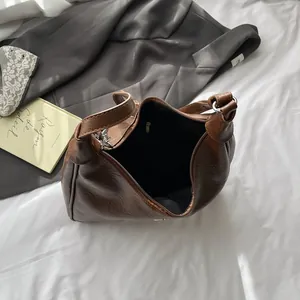 Detail of dark brown leather tote showing metal rings and spacious fabric interior