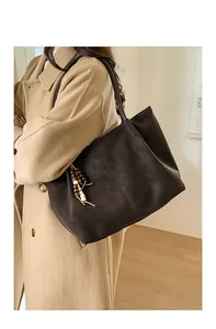 Macro detail of dark brown matte suede tote bag with wooden bead tassel and long strap
