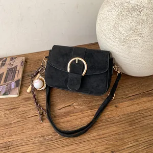 Minimalist black matte shoulder bag with golden buckle and a baseball charm pendant