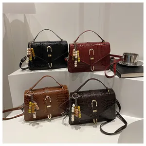 Detailed view of crocodile pattern crossbody bags in four colors with beaded tassel decor