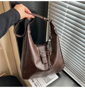 Detail view of coffee brown vintage tote bag with metal buckle and woven knot pendant