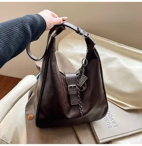 Detail of vintage brown soft leather shoulder bag with metallic tassel and adjustable strap