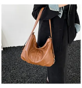 Detail of soft brown leather tote bag with circular embossed design and pebble texture