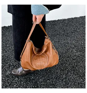 Detailed texture of brown leather Hobo bag with circular embossed logo and handle