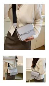 Detail view of silver square crossbody bag with wide black strap and metal buckle closure