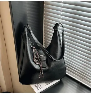 Detail of black pebbled leather texture on vintage hobo bag with metallic buckle and woven charm