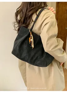 Black suede tote bag with decorative wooden beads shown from a side-rear perspective