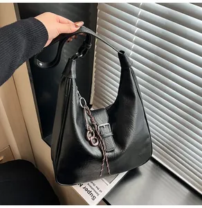 Close-up of black crossbody bag featuring a metal buckle and woven cord ornament