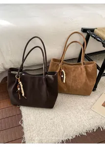 Detailed close-up of suede tote bags with wooden bead tassels in dark brown and camel