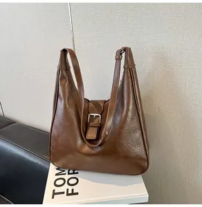 Close-up of vintage dark brown PU leather shoulder bag with silver buckle on a bench