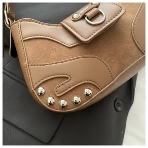 Close-up of brown patchwork shoulder bag with suede textures and silver rivet details