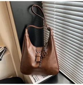 Detail of dark brown hobo bag with pleated texture, metal ring and braided strap charms