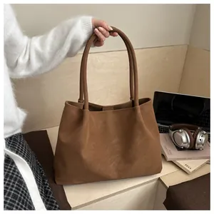 Dettaglio di una borsa tote marrone su una scrivania moderna con laptop e accessori