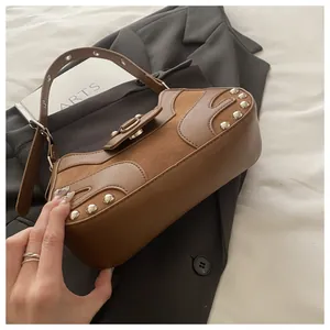 Close-up of vintage brown leather underarm bag with silver rivets and metal ring detail