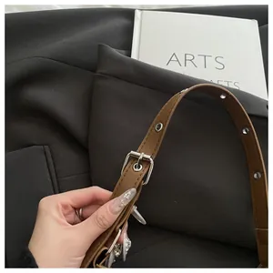 Close-up of adjustable brown leather shoulder strap with silver buckles and eyelets