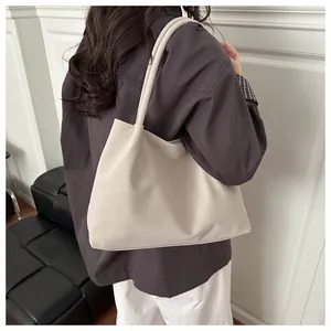 Borsa tote minimalista in pelle PU beige indossata da una modella in un interno