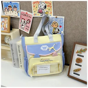 Detail of multi-pocket student tote bag featuring a transparent display window and charms