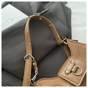 Detail of a brown leather shoulder bag with JINGPIN metal plate and vintage eyelets
