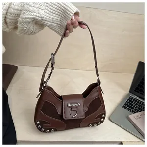 Close-up of rivet details and silver metal buckle on brown shell-shaped shoulder bag