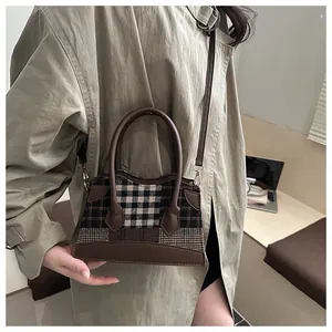 Détail du sac seau à carreaux avec garniture en cuir marron et boucles dorées