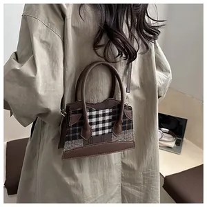 Détail du sac seau à carreaux vintage avec bordure en cuir marron et détails dorés