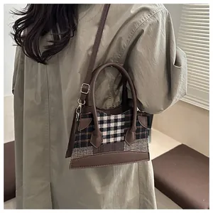 Détail du sac seau à carreaux vintage avec poignées en cuir marron et bandoulière réglable