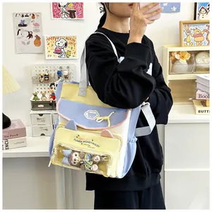 Detail of multi-color canvas tote bag featuring clear window with plush bear and cat ear design