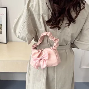 Rosa Plissee-Handtasche mit Seidenschleife und Silberkette, präsentiert am Modell