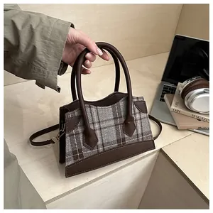 Vue de dessus d'un sac seau à carreaux avec cuir marron près d'un ordinateur et livres