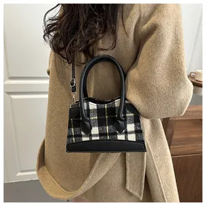 Détail du sac seau en laine à carreaux avec poignée en cuir noir et boucles dorées